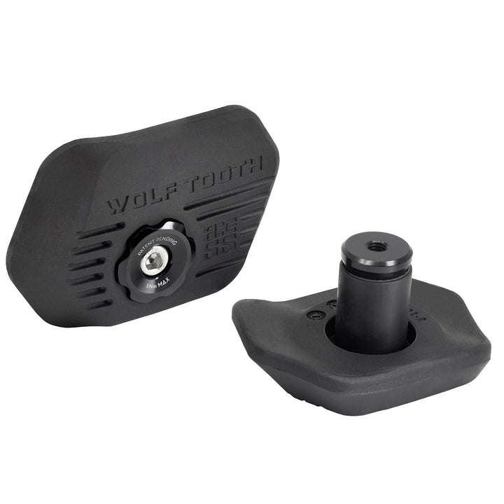 Two black Wolf Tooth bike handlebar grips shown on a clean white background, one displaying the side with the brand name and the other showing the front with the mounting post.